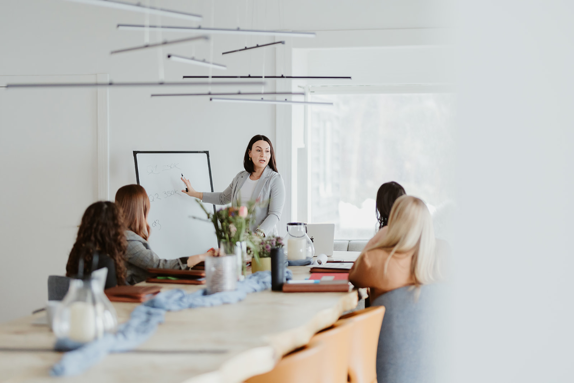 A leader presenting to her team around a conference table in a bright, modern office